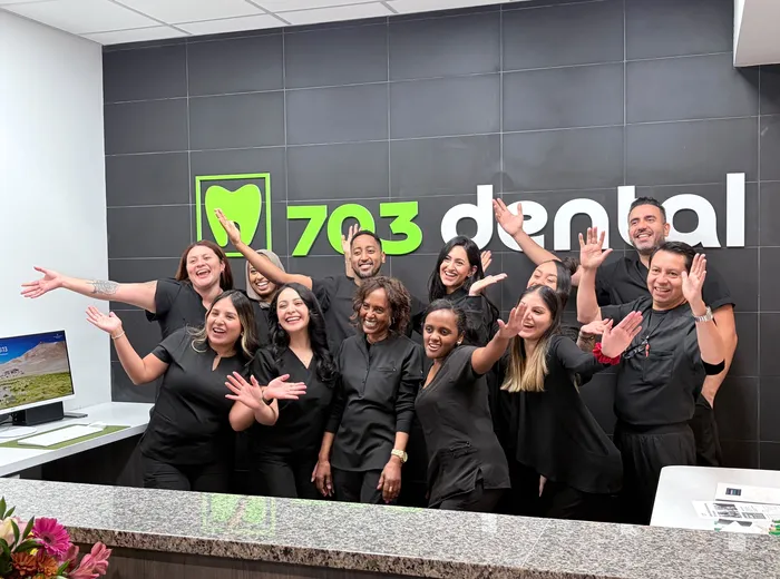 The 703 Dental team celebrating at the front desk of the Woodbridge, VA office